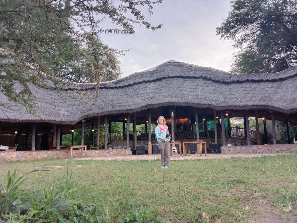 Guest in front of an authentic thatched-roof luxury safari lodge in Tanzania