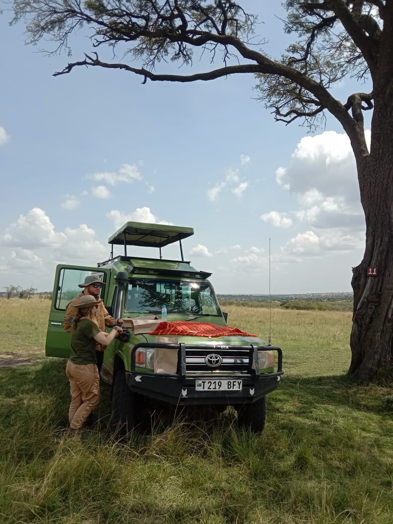 Olympus Adventure custom 4x4 safari cruiser with picnic lunch prepared on the hood under an acacia tree in the Serengeti