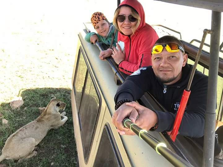 Family enjoying an up-close lioness sighting from an Olympus Adventure safari vehicle